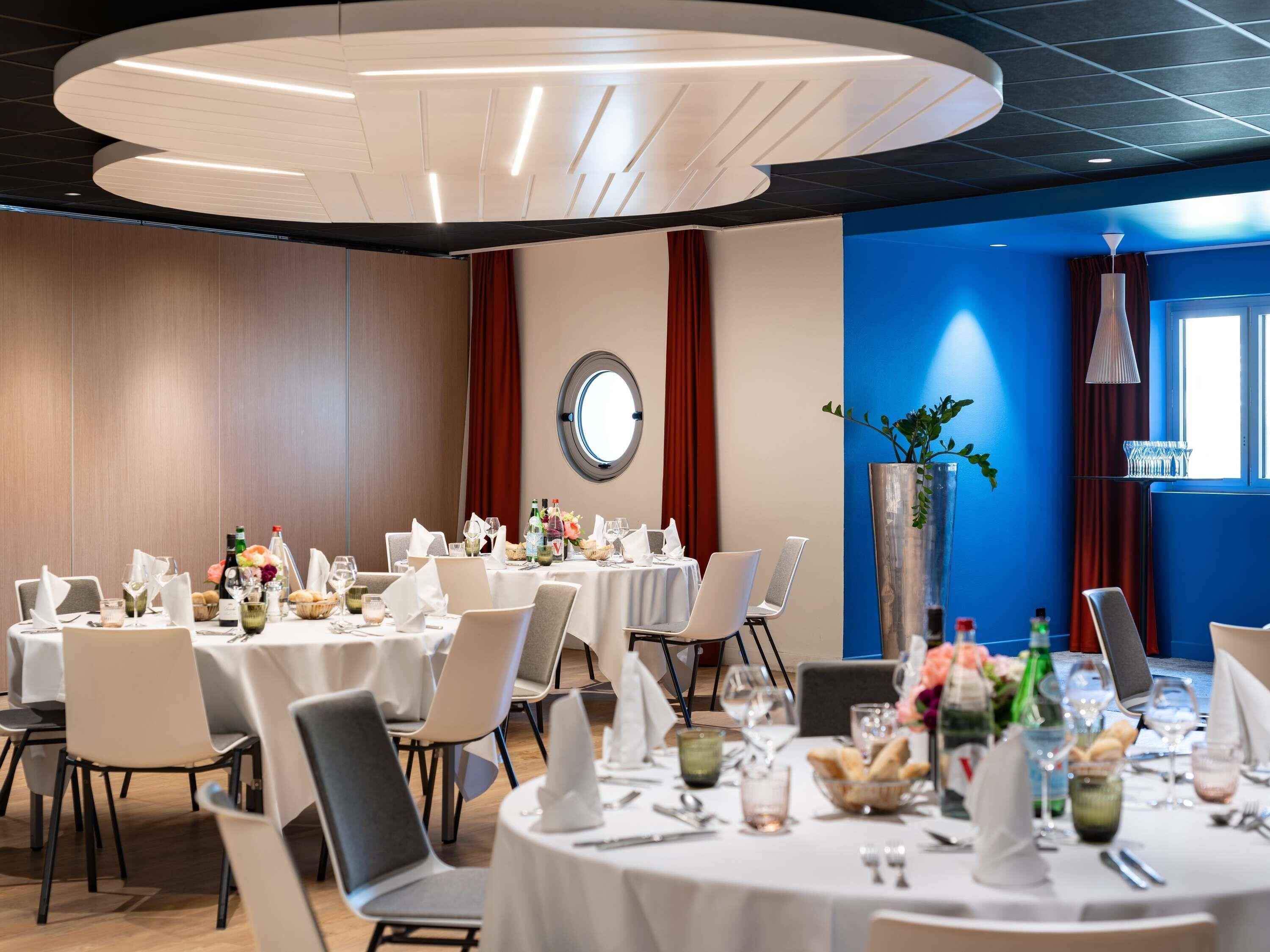 A conference room with round tables, white tablecloths, and chairs.