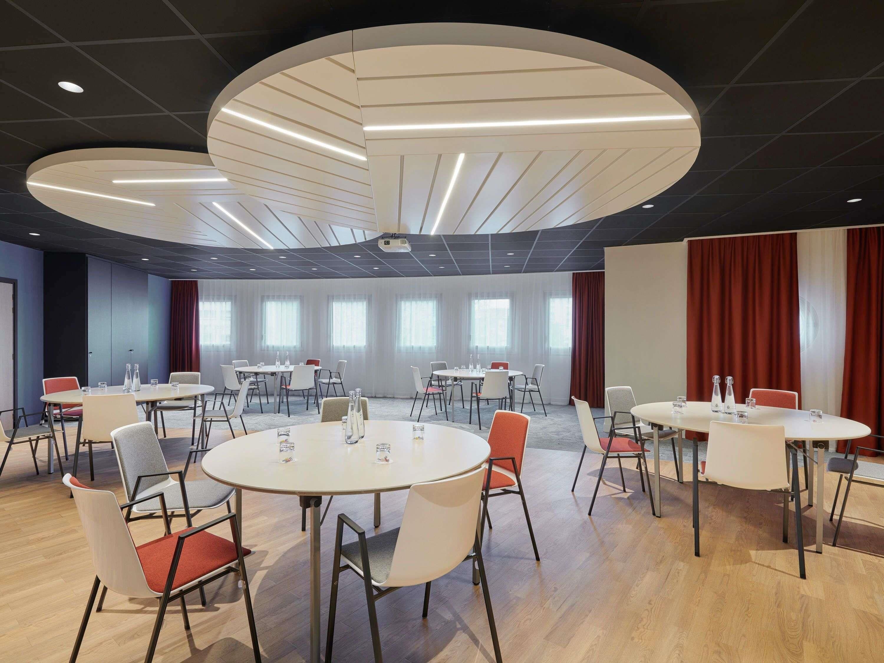 A conference room with round tables, chairs, and a ceiling projector.
