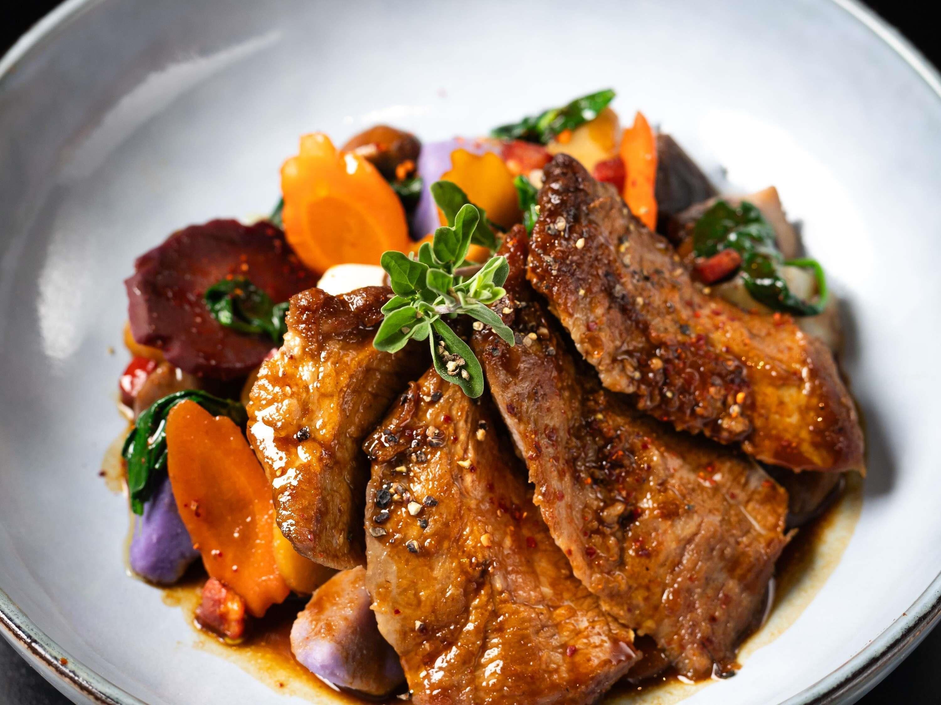 A plate of food with meat, vegetables, and a garnish.