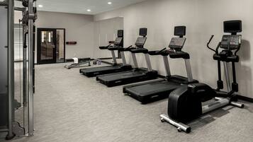 A gym with treadmills, a weight machine, and a digital display.