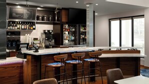 A modern bar area with a long counter, bar stools, and a wine and spirits display. - Courtyard by Marriott Portland Beaverton (Beaverton)