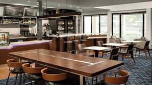 A modern bar area with a long counter, stools, and a menu board. - Courtyard by Marriott Portland Beaverton (Beaverton)