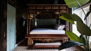 A four-poster bed with intricate carvings, a large plant, and a patterned floor. - Kasteel Kerckebosch (Zeist)