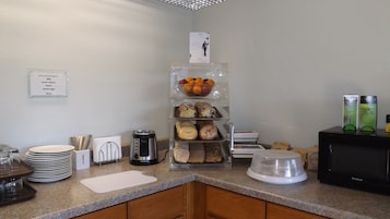Um balcão de café da manhã com diversas opções de alimentos, incluindo frutas, doces e acompanhamentos.