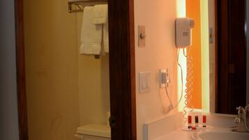 Ein Badezimmer mit Toilette, Dusche, Waschbecken und einem Fön an der Wand.