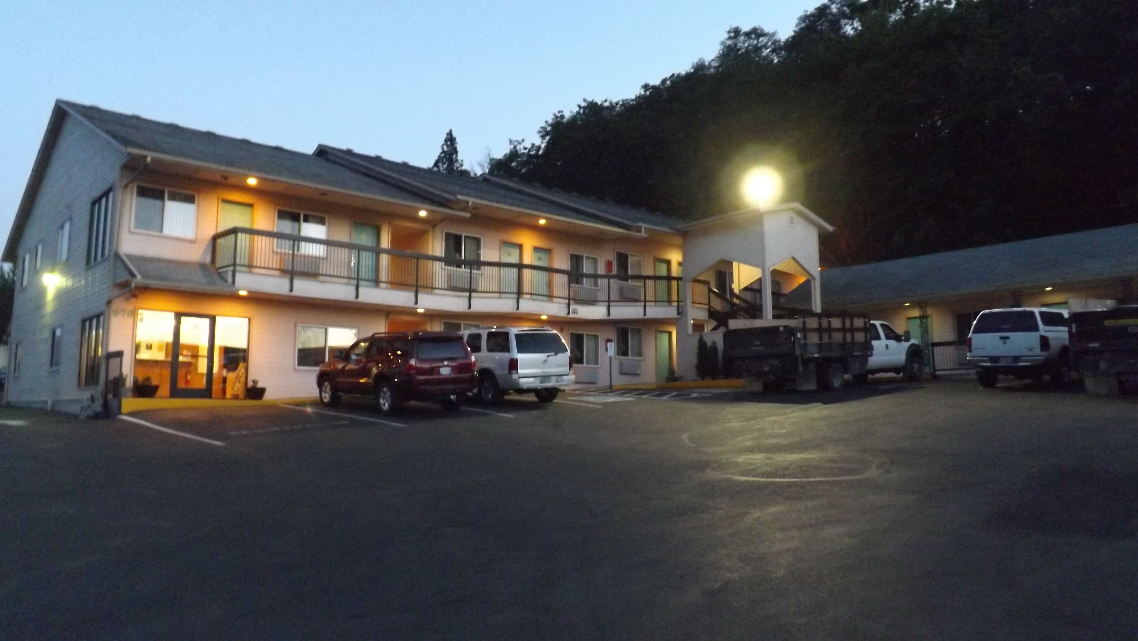 A motel with a two-story structure, a covered parking area, and a truck parked outside.