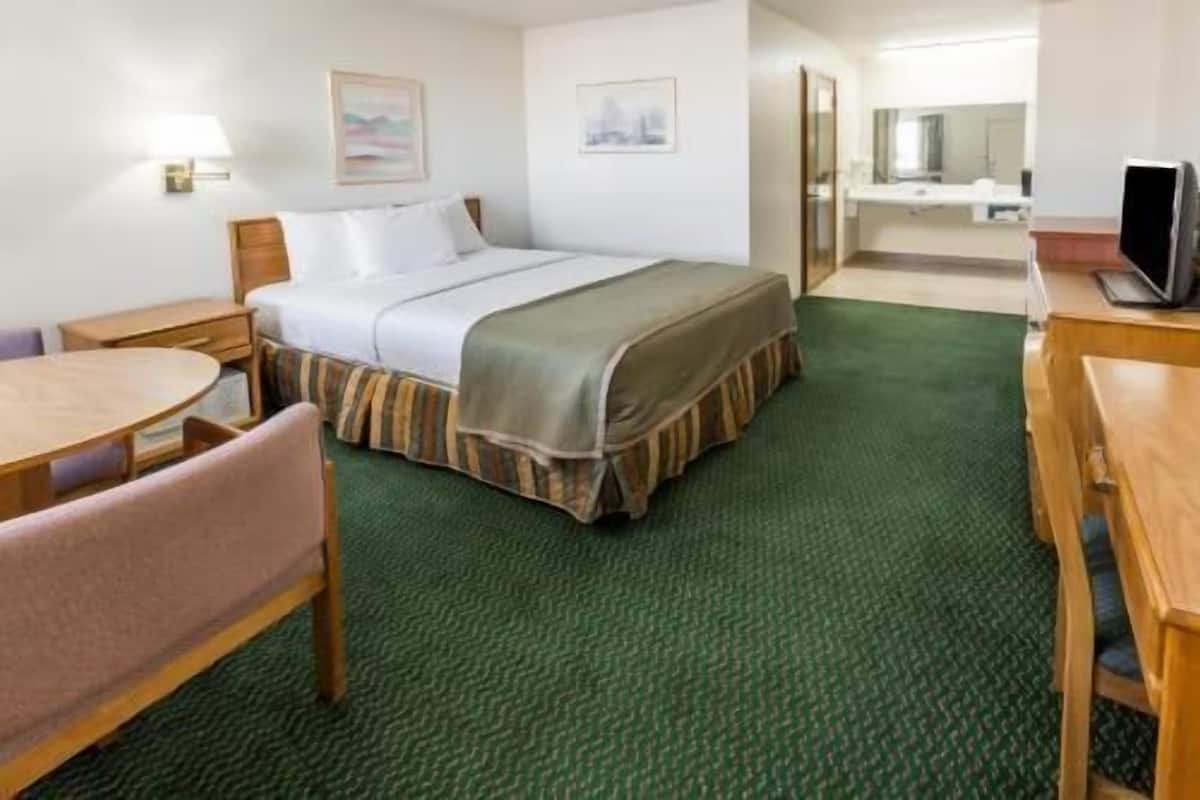 Una habitación de hotel con una cama, un escritorio, una silla, una lámpara y un televisor.