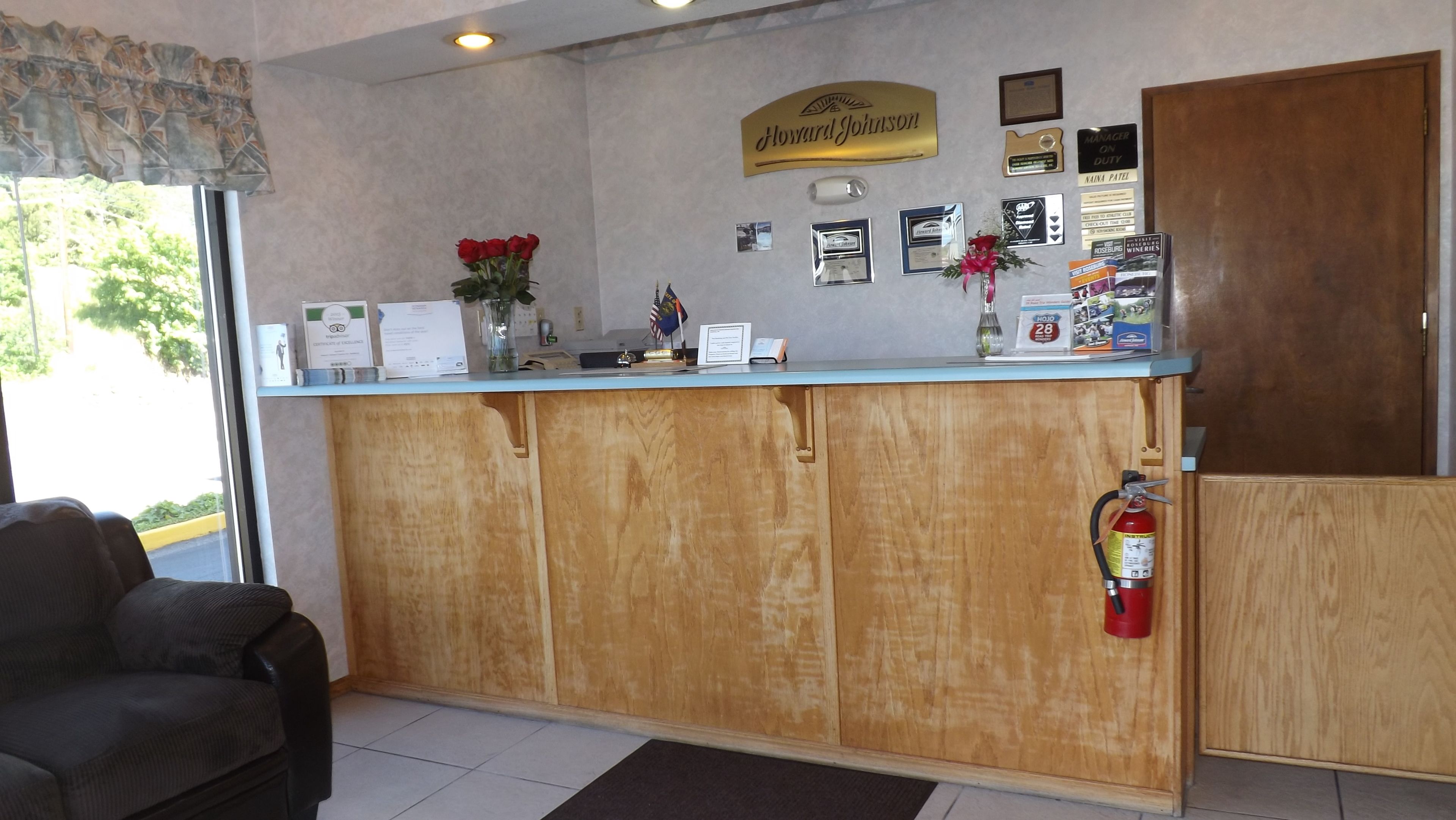 A reception desk with a wooden counter, certificates, a fire extinguisher, and a sign reading "Howard Johnson."
