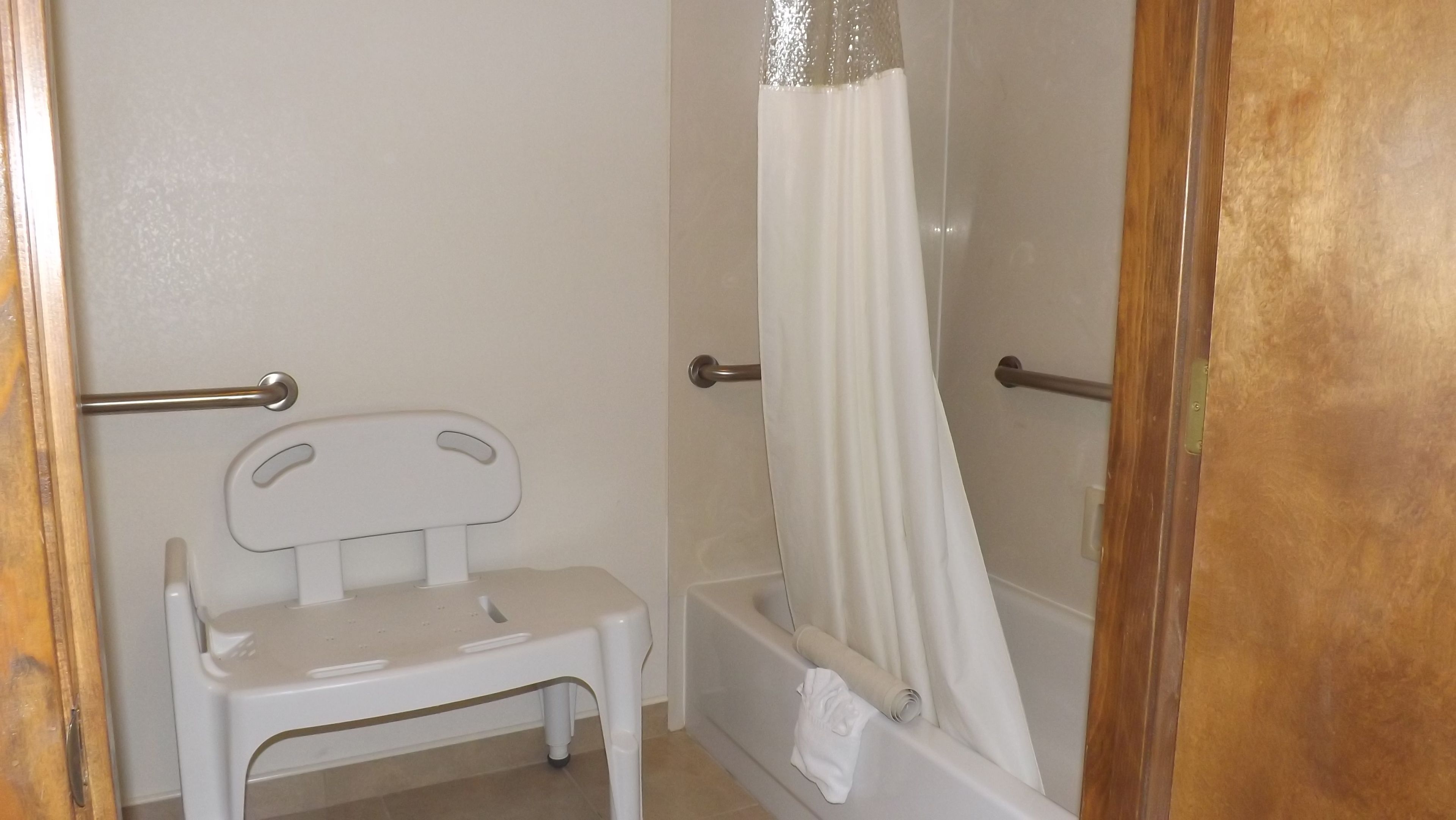 Ein Badezimmer mit Dusche, einem weißen Stuhl und einem Handtuchhalter.