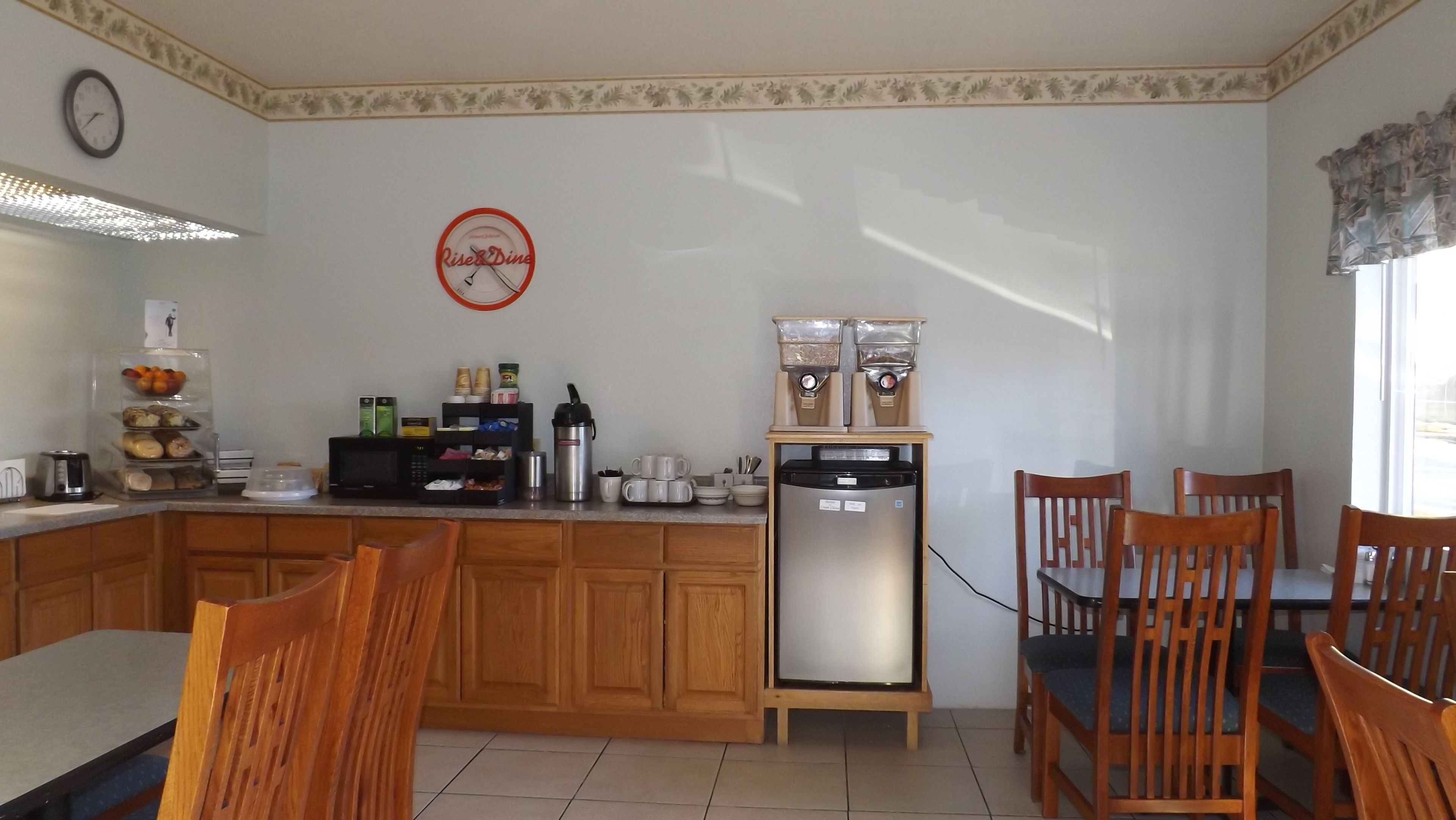 Eine Küche mit Holzausstattung, einem Kühlschrank, einer Kaffeemaschine und einer Uhr an der Wand.