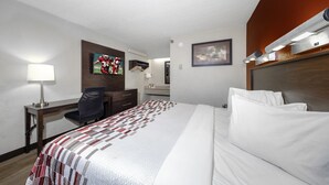 A hotel room with a bed, desk, chair, TV, and artwork on the walls. - Red Roof Inn Tampa - Brandon (Tampa)