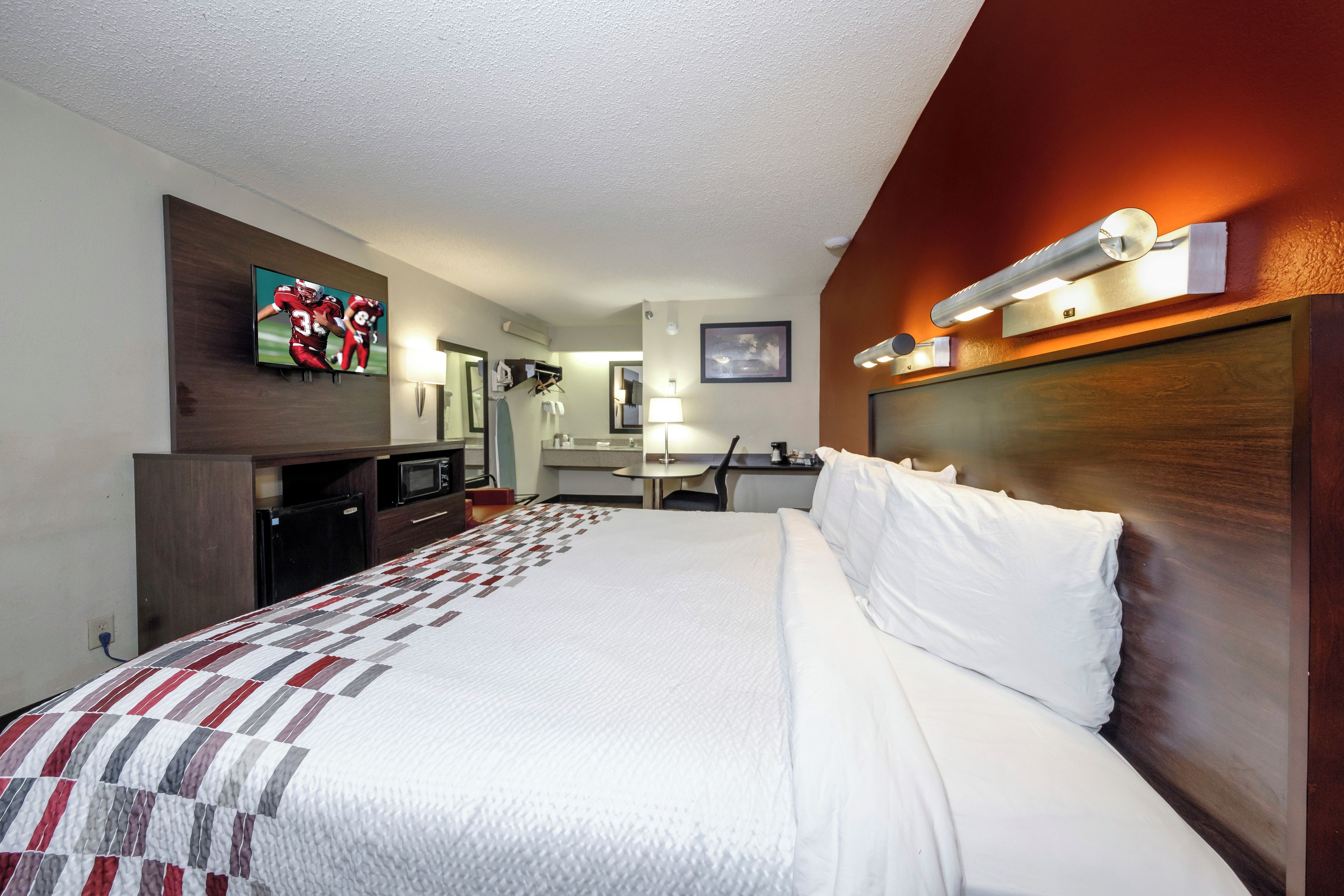 Una habitación de hotel con cama, televisión, escritorio y espejo.