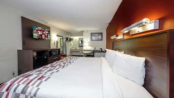 A hotel room with a bed, a television, a desk, and a mirror.