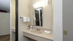 A hotel bathroom with a sink, mirror, towel rack, and a bottle of hand soap. - Red Roof Inn Tampa - Brandon (Tampa)