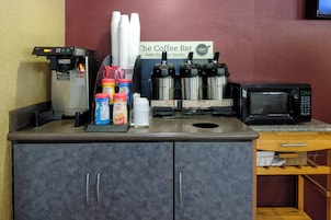 Una estación de café con cafetera, máquinas de espresso y un microondas.
