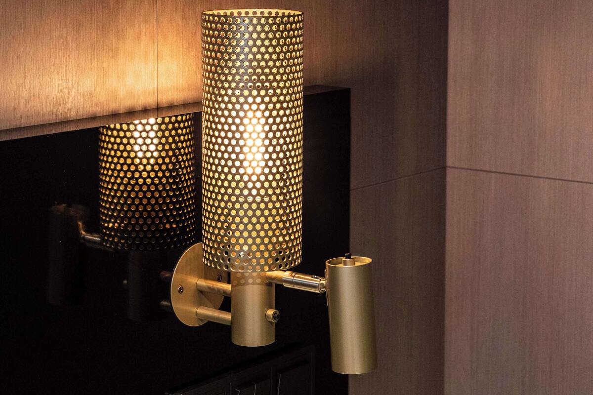A wall-mounted light fixture with a perforated cylindrical design.