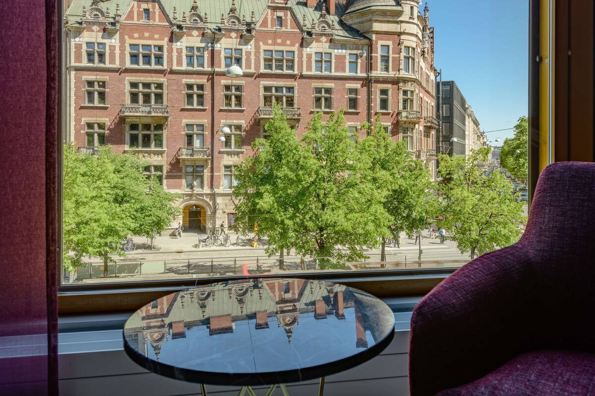 A room with a view of a historic building, a round table, and a purple chair.