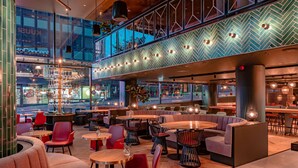 Un restaurante moderno con techo alto, vigas a la vista y una variedad de opciones de asientos, incluyendo mesas y cabinas.