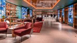 Un moderno vestíbulo de hotel con zona de bar, asientos y una escalera.