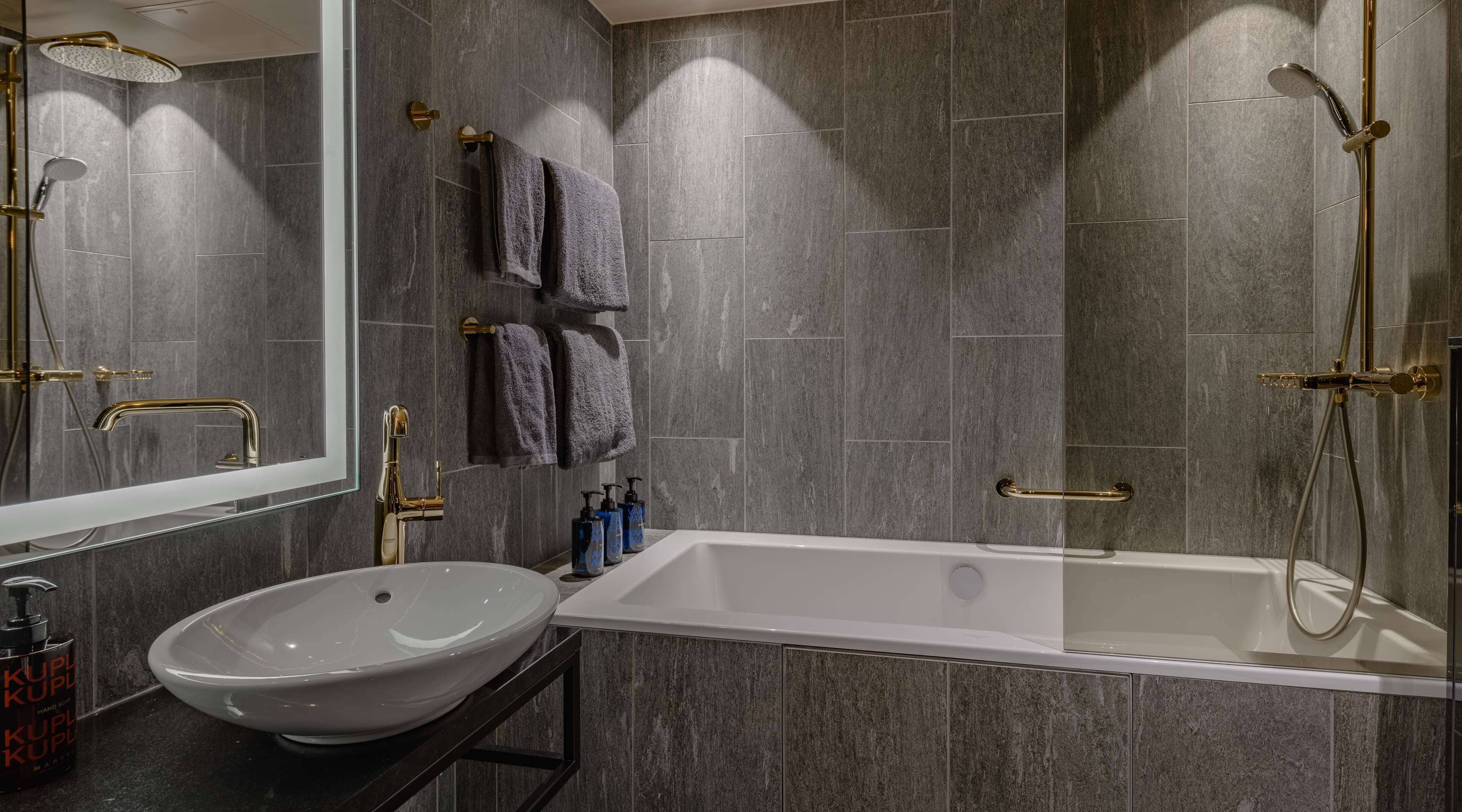 A modern bathroom with a large bathtub, a vessel sink, and a shower with a handheld showerhead.