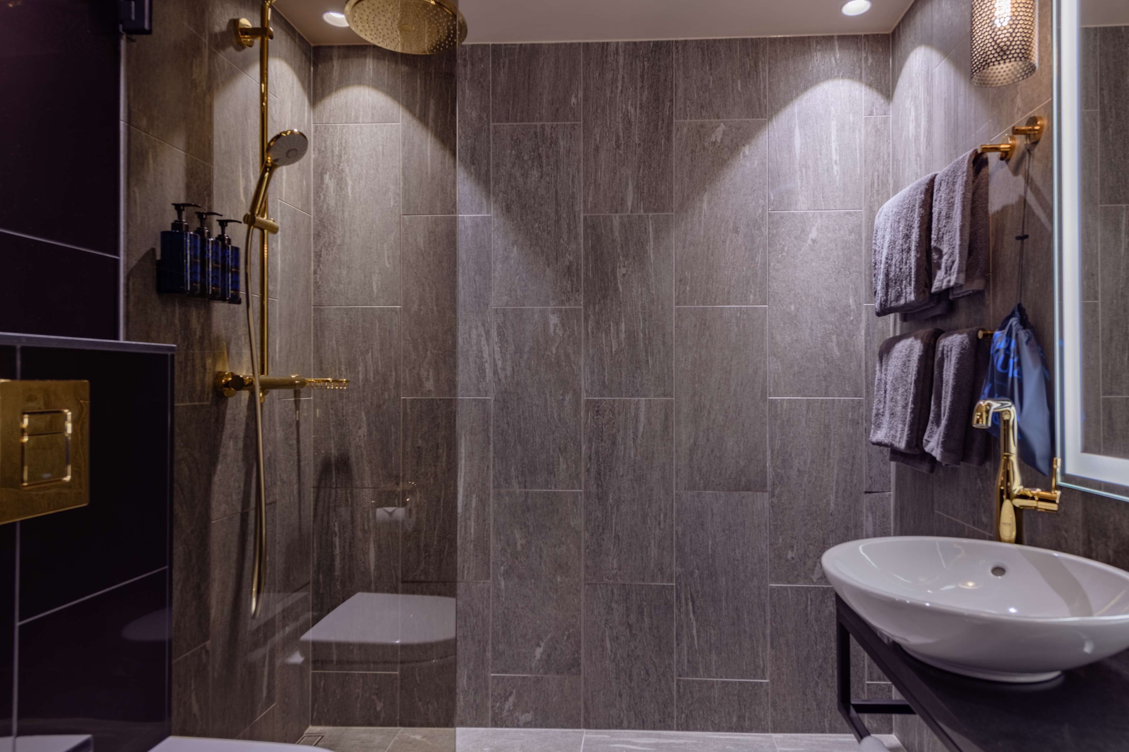 A modern bathroom with a shower, a sink, and a towel rack.