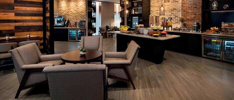 A modern kitchen with a central island, bar area with stools, and a seating area with chairs.