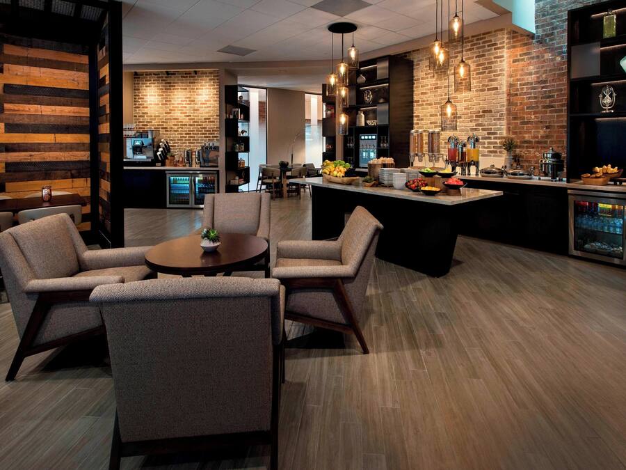 A modern kitchen with a central island, bar area with stools, and a seating area with chairs.