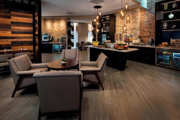 Cozinha moderna com ilha central, espaço bar com banquetas e área de estar com cadeiras.