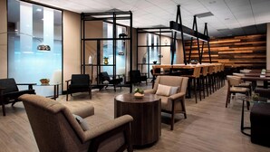A modern lounge area with comfortable seating, a bar, and large windows.