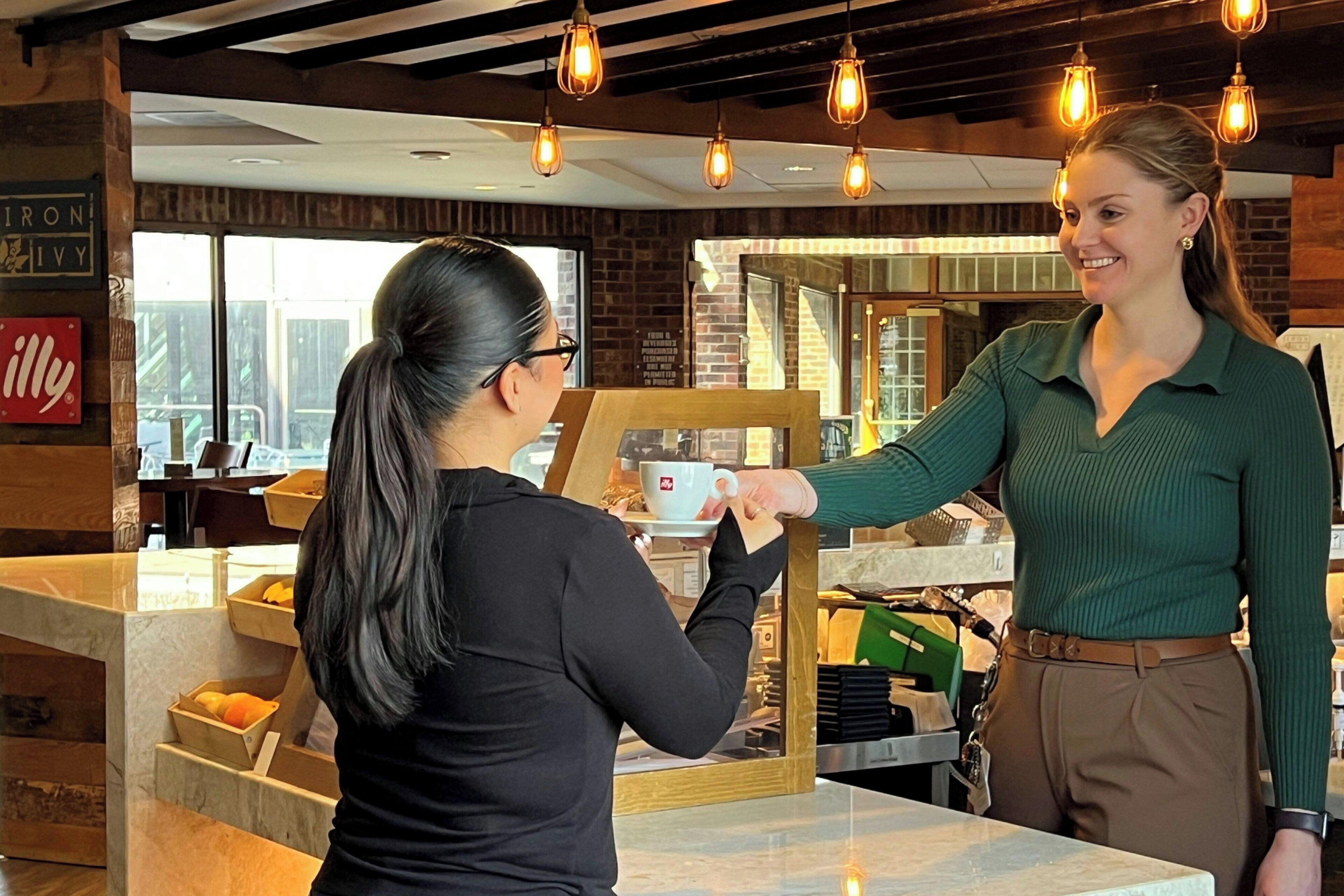 A coffee shop interior with a marble counter, wooden accents, and hanging light fixtures.