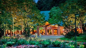 A brick building with a large entrance and a well-maintained garden with colorful flowers.