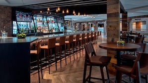 A bar area with a long counter, multiple stools, and a round table with chairs.