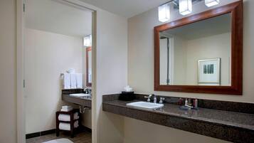 Un bagno moderno con lavabo su piano in granito, uno specchio grande e un porta asciugamani.