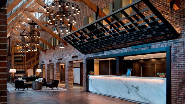 A spacious lobby with a reception desk, seating area, and a staircase leading to upper floors.