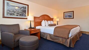 A hotel room with a bed, a chair, a nightstand, and two wall-mounted lamps.