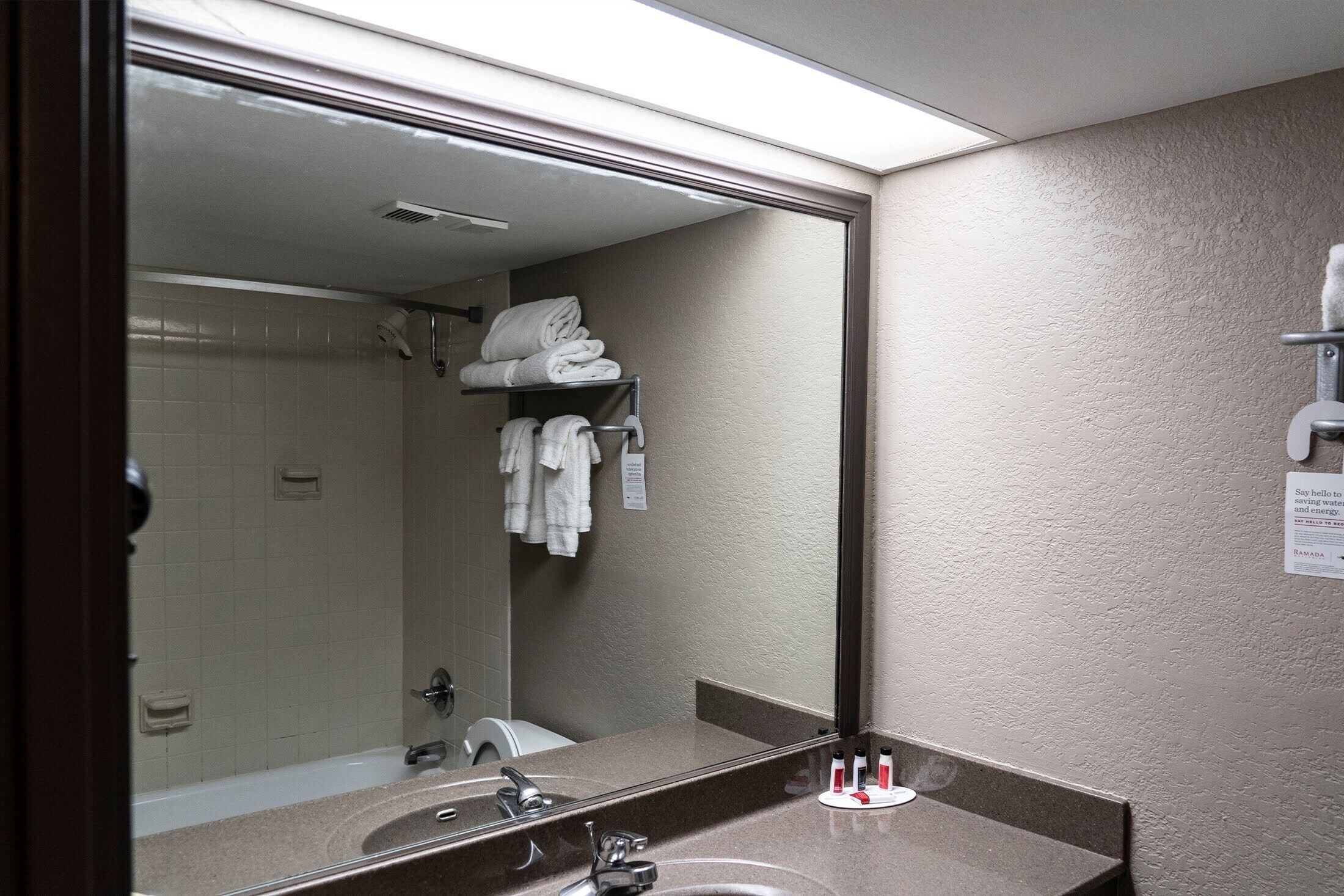 Un baño con lavamanos, espejo y toallero.