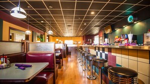 Ein Restaurant mit Sitzgelegenheiten in Form von Boxen, hohen Hocker und einer Bar.
