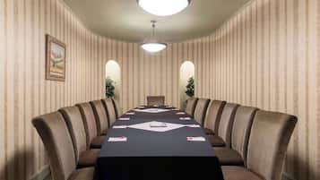 Een vergaderzaal met een lange tafel, stoelen en een plafondlamp.