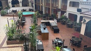 Ein mehrgeschossiges Atrium mit Außenmöbeln, einem Pool und einem überdachten Bereich mit rotem Dach.