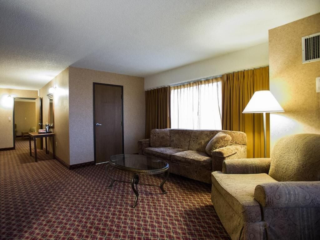 A hotel room with a sofa, armchair, and a small table.