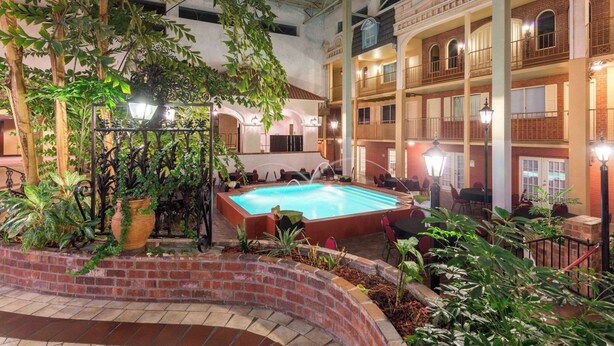 Ein Poolbereich im Innenbereich mit Backsteinwand, Topfpflanzen und Sitzgelegenheiten rund um den Pool.