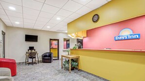 Un espace d’accueil avec un mur rouge et jaune, une horloge et une enseigne Days Inn.