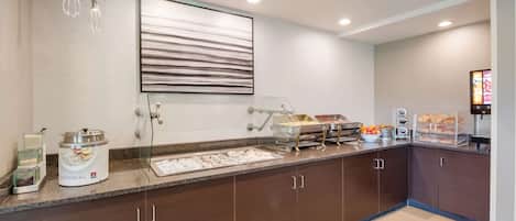 A modern kitchen with a breakfast bar, a coffee station, and a large framed artwork on the wall.