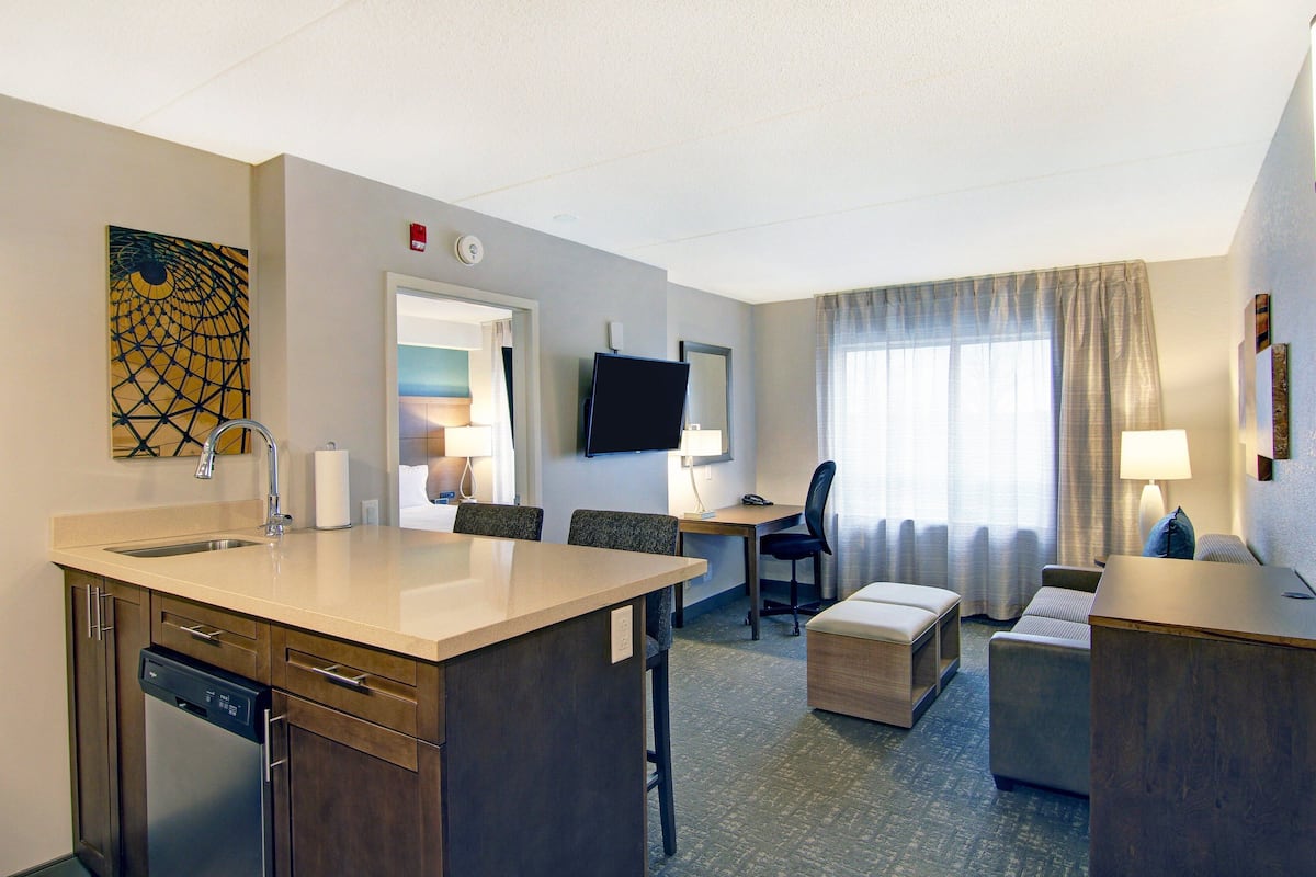 Une chambre d’hôtel équipée d’une kitchenette, d’un téléviseur à écran plat, d’un canapé et d’un coin repas.