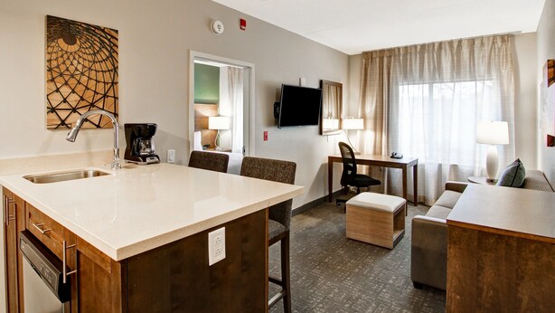 Habitación de hotel con kitchenette, comedor, sofá y televisor.