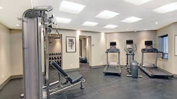 A gym with various exercise equipment including a treadmill, elliptical, and weight machines.
