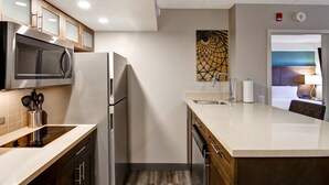 Una cocina compacta con microondas, refrigerador y lavamanos.