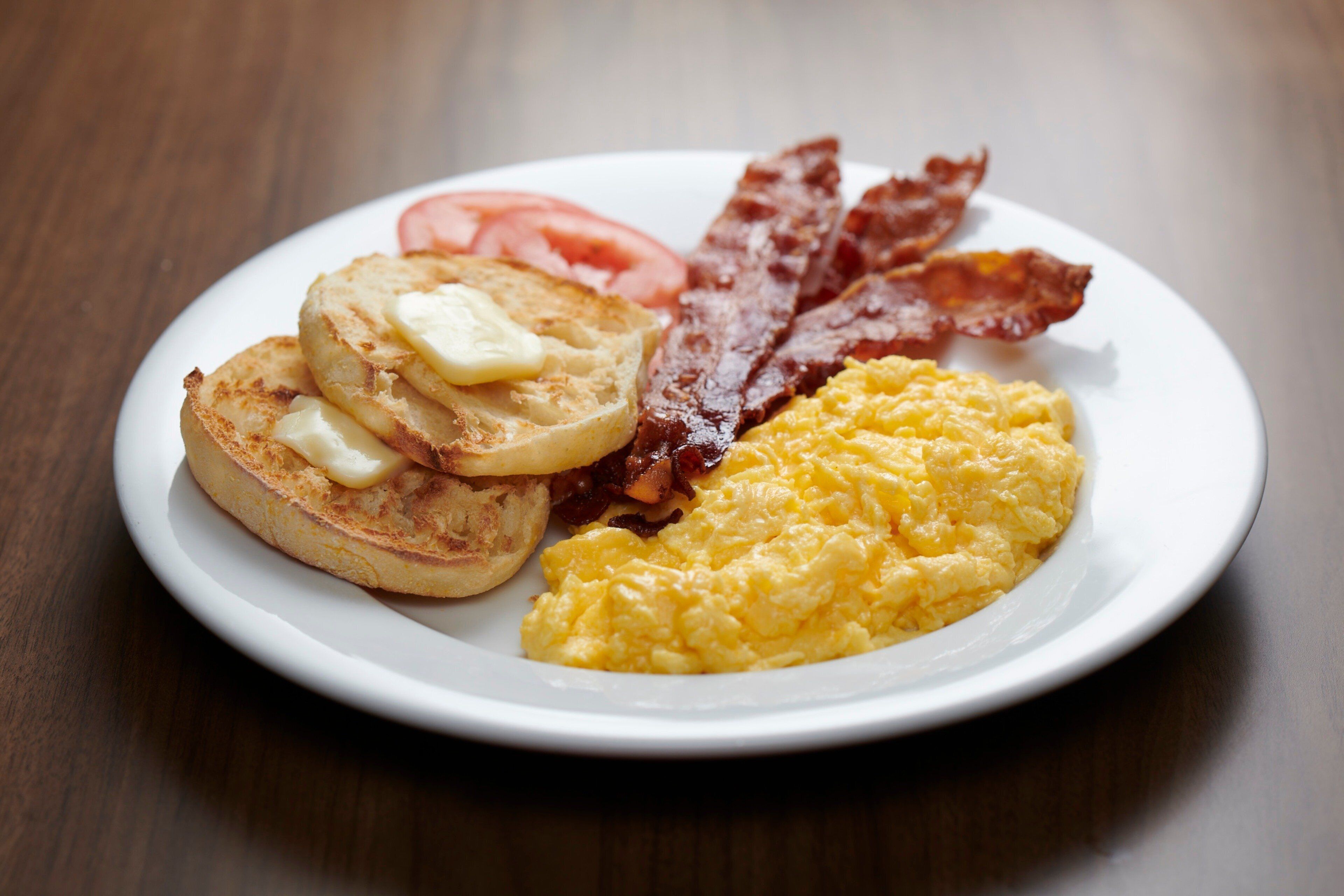 A plate with eggs, bacon, toast, and tomatoes.