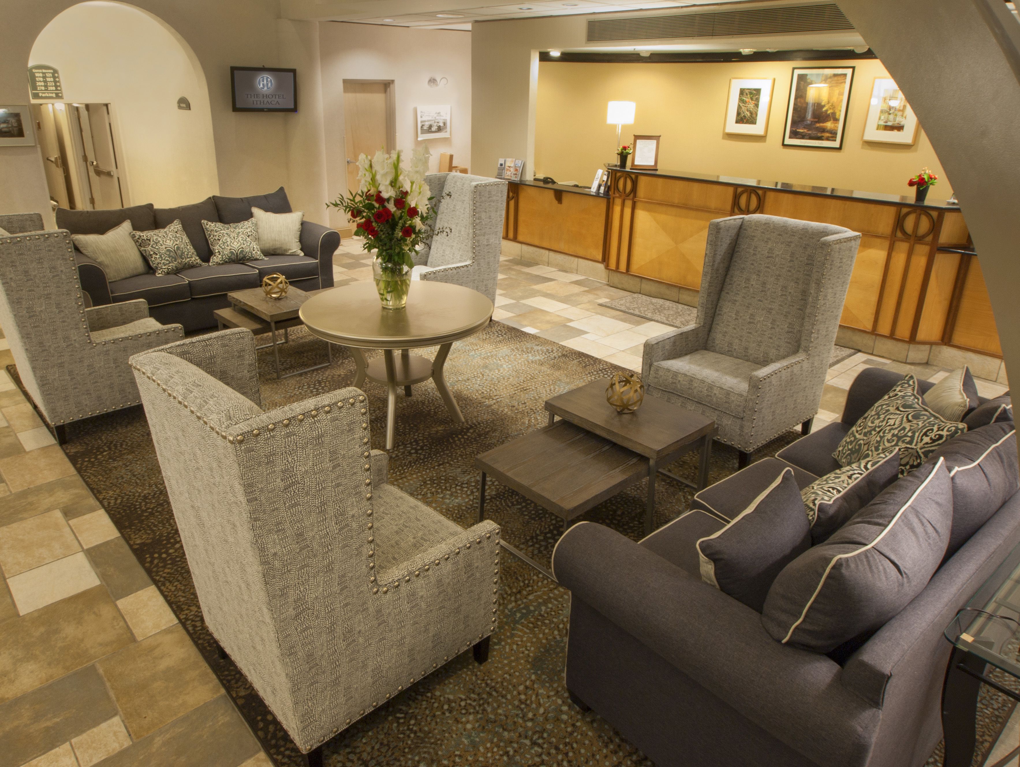 Un vestíbulo de hotel con arreglos de asientos, una mesa de recepción y un mostrador de check-in.