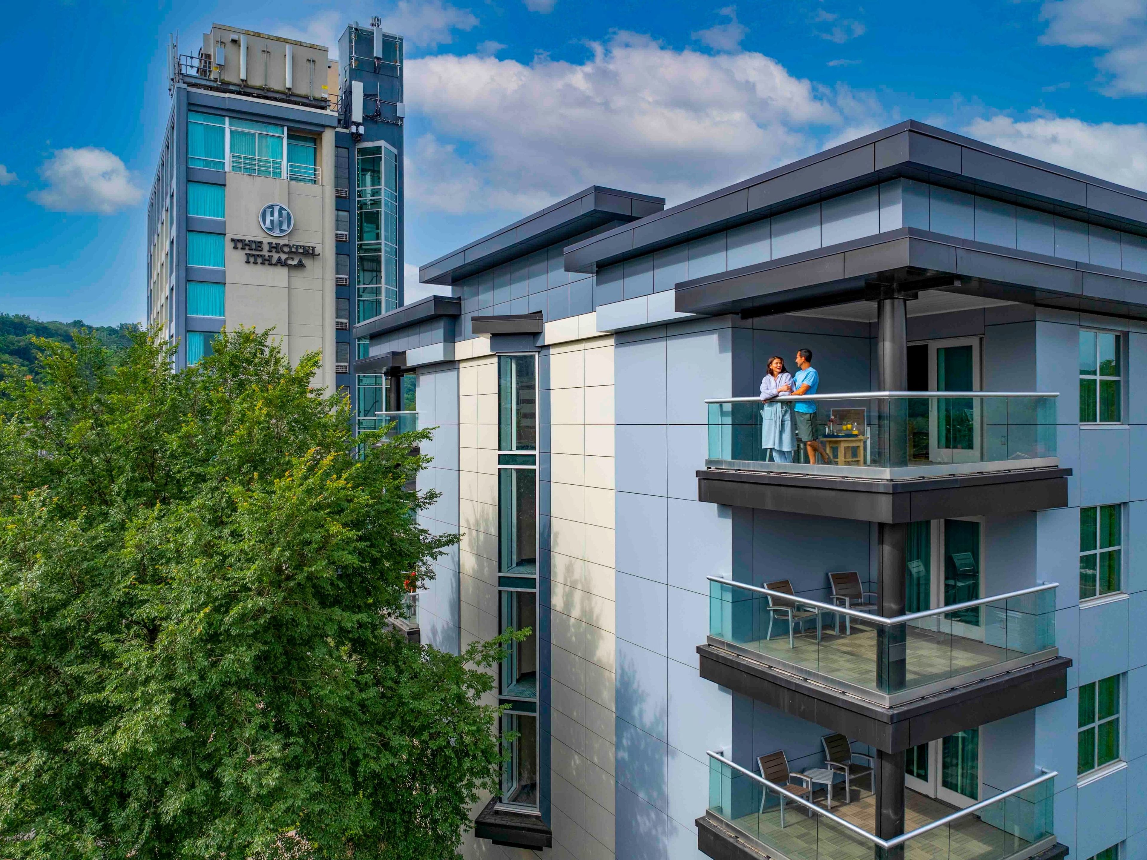 A hotel with a modern design, featuring multiple balconies with glass railings and outdoor seating.
